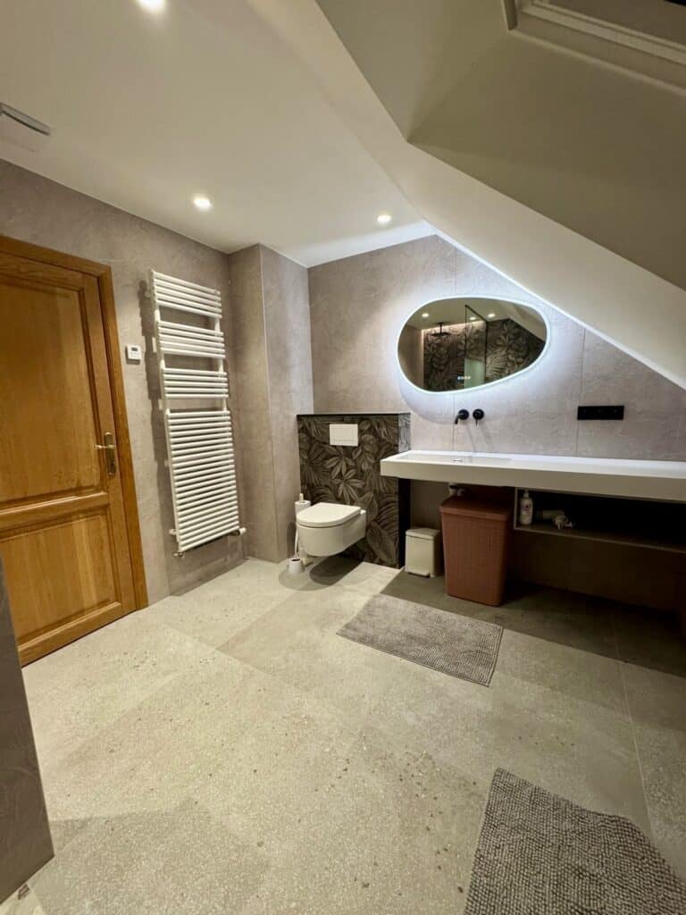 Aménagement de salle de bain moderne par Amebath à Verviers : receveur extra-plat, paroi en verre opacifié, baignoire encastrée et revêtement mural à motif tropical.